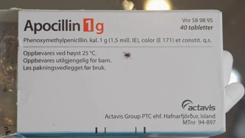 Tick walking over Apocillin 1g Actavis antibiotic package symbolizing infection 스톡 동영상 319653133