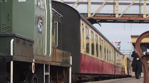 A ticket inspector walks past old carriages and steam engine 스톡 동영상 73432215