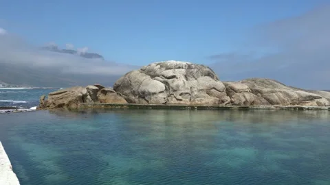 Tidal pool by huge beach boulders along a rocky shoreline Stock Footage 332177973