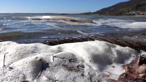Tidal sea waves with foam in the background is a sunken boat near the shore Stock Footage 235442264