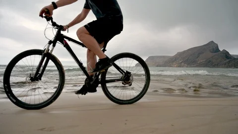 Tidal wave comes in after man on bicycle passes by on the beach Stock Footage 114505854