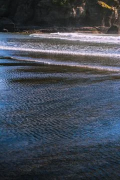 Tidal waves gently rolling over black sand of Piha Beach Stock Photos