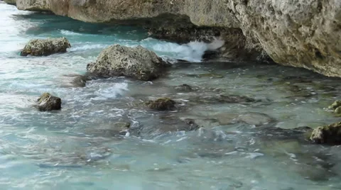 Tidal waves from the oceam slapping up against shore rocks and beach Stock Footage 33588864