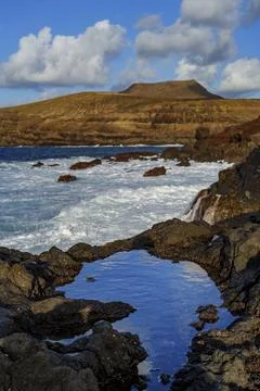 Tide Pool Reflection on Rocky Coast With Waves and Hills Stock Photos