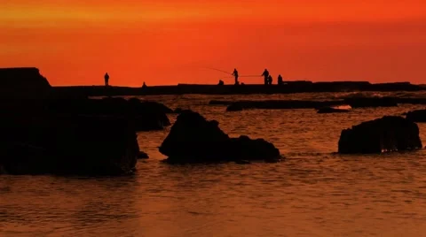 The tide reflects a brilliant sunset as Fishermen relax Ceasarea Israel Stock Footage 59685688