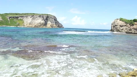 Tide with waves and cliffs in the distance in the coastal area of Guadeloupe Stock Footage 247512990