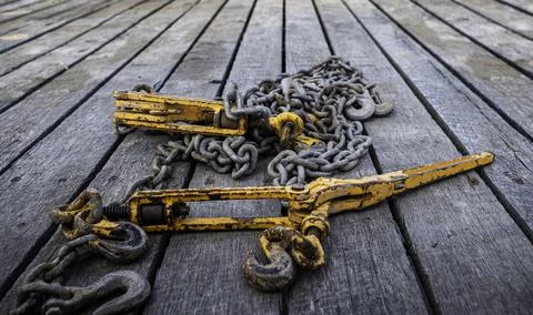 Tie down chains and binders on wood boards of flatbed trailer. Stock Photos