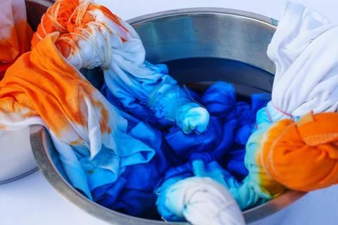 Tie Dyeing Process with Bright Orange and Blue Liquid in Metal Bowl 스톡 사진