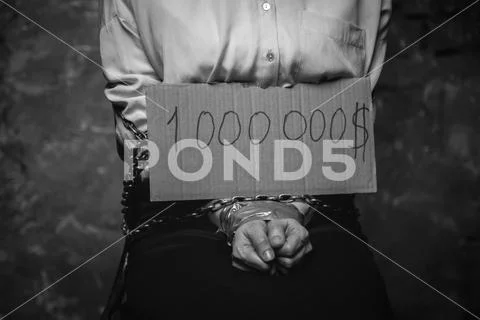 Tied weak victim showing a sign with a ransom sum Stock Photos