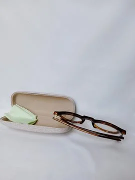 Tiger pattern eyeglass and green lens cleaner fabric on opened case edge. Stock Photos