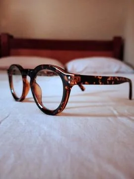 Tiger pattern eyeglass on white bedspread Stock Photos