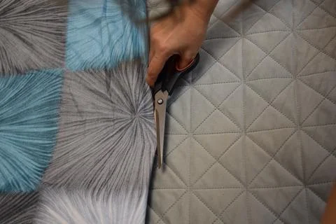 Tight Close Up of Sharp Tailor Shears Cutting Fabric on Quilted Base Foto stock
