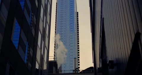 Tight corridor of tall buildings opens onto slender central tower, its mirrored Stock-Footage 314467006