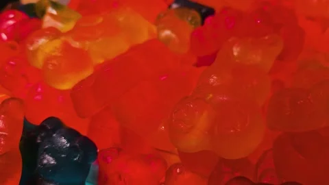 Tight shot of gummy bear candy filling a market tray, with glowing translucent Stock Footage 341402802