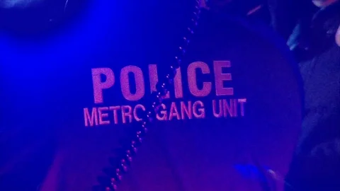 Tight shot of metro gangs jacket on police officer at night. Stock Footage 99369953