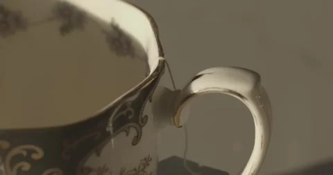 Tight in shot of wrapping tea bag around a teacup and pouring water in the cup Stock Footage 250070034