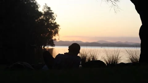 Tight in shot of young men sitting at Myall lakes watching the sunset. Stock Footage 250070513