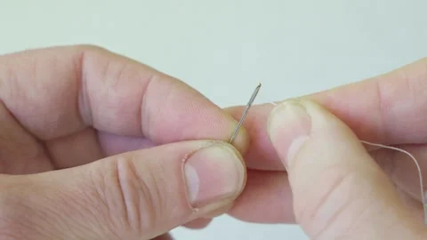 Tightening thread into eye of needle, close-up. Video stock 289275840