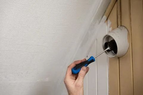 Tightening wall lamp socket with screwdriver during home repair Stock Photos