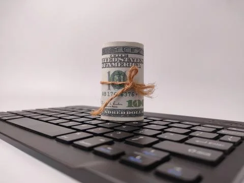 A tightly rolled stack of American one-hundred-dollar bills tied with brown.. Stock Photos
