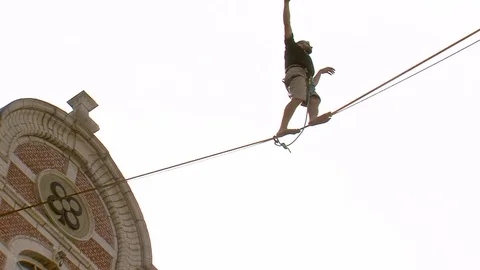 Tightrope Walker Balancing On A Rope between buildings Stock Footage 69944991