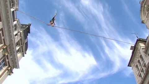 Tightrope Walker Balancing On A Rope between buildings Stock Footage