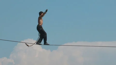 The tightrope Walker is on the rope stretched high in the mountains. Stock Footage 86361820