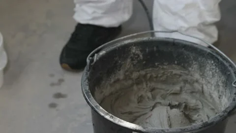 Tile adhesive is mixed with an orange electric drill in a bucket. Video stock 200222693