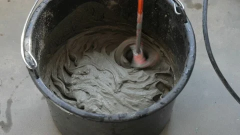 Tile adhesive is mixed using an electric drill in a bucket. Video stock 152354504
