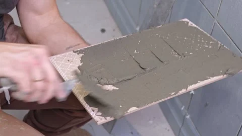 Tile adhesive spreading. Tiling mortar application. Worker smoothing adhesive Stock Footage 328630181