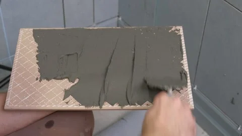 Tile adhesive spreading. Tiling mortar application. Worker smoothing adhesive Stock Footage 328630312