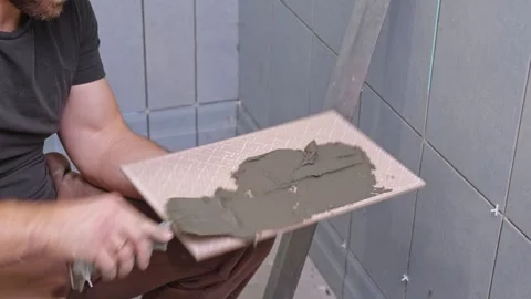 Tile adhesive spreading. Tiling mortar application. Worker smoothing adhesive Stock Footage 330450966