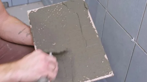 Tile adhesive spreading. Tiling mortar application. Worker smoothing adhesive Stock Footage 333126301
