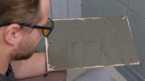 Tile adhesive spreading. Tiling mortar application. Worker smoothing adhesive Stock Footage 333479771