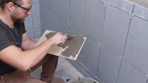 Tile adhesive spreading. Tiling mortar application. Worker smoothing adhesive Stock Footage 333479832