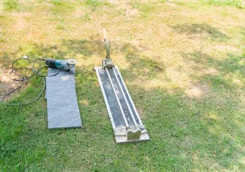 The tile cutter is placed on the grass. Stock Photos