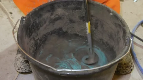 Tile glue is mixed with an electric drill in a bucket. Video stock 199836714