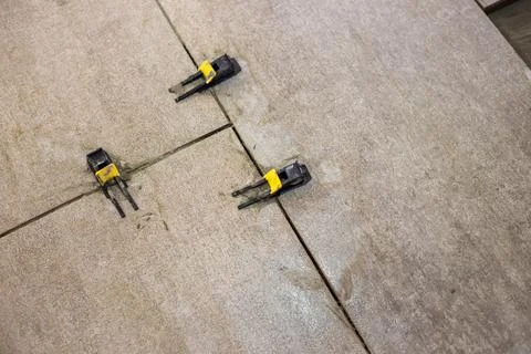 Tile leveling clips are installed between laid floor tiles, ensuring a uniform 스톡 사진