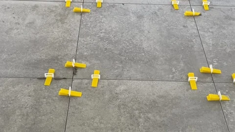 Tile leveling system on concrete floor, showing yellow spacers for precise .. Stock Footage 328713534