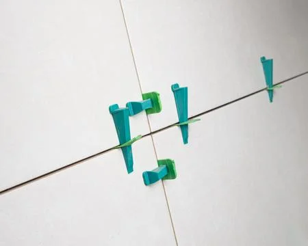 Tile leveling system with plastic clips and wedges, shot while the tile mor.. Stock Photos