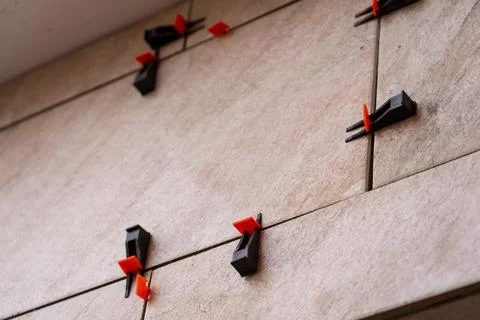 Tile leveling system with plastic clips and wedges, shot while the tile mor.. Фото