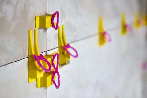 Tile leveling system with yellow wedges, pink clips used for precise ceramic  Stock Photos