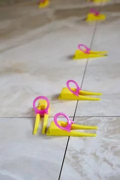 Tile leveling system with yellow wedges, pink clips used for precise ceramic  Photos