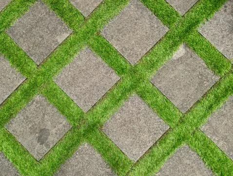 Tile pavement close-up with artificial green grass Stock Photos