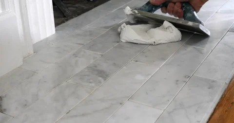 A tile setter's hands spreading white grout on a carrara marble. Stock Footage 129068102