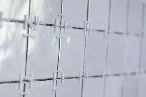 A tile wall under construction. The wall is being tiled with small bumpy re.. Stock Photos