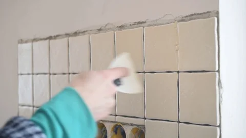 Tile worker filling gaps between tiles with grout Stock Footage 74805611