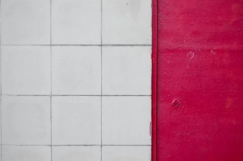 Tiled gray wall of a building with a red iron door Foto stock