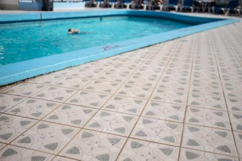 Tiled poolside and swimmer in the background Stock Photos
