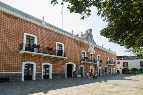Tiled town hall facade with clock tower and small group of people walking Stock Photos